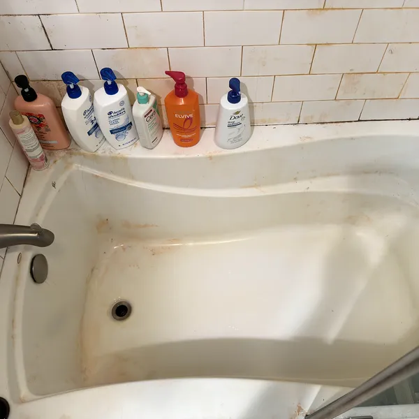 Bathtub with rust stains and soap scum before a deep cleaning