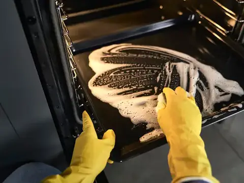 Gloved hands cleaning the inside of an oven